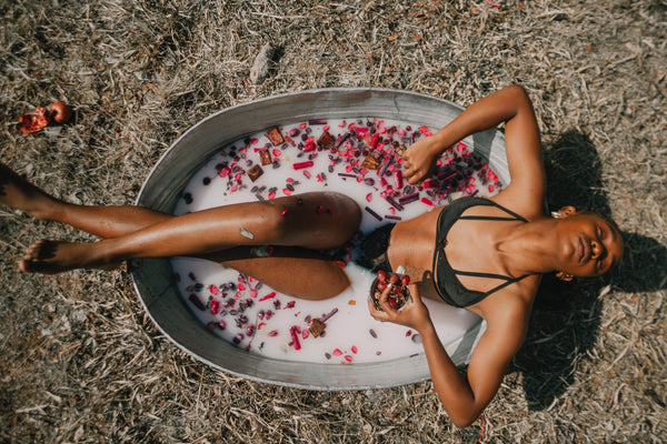 black woman in a metal tub with rose petals